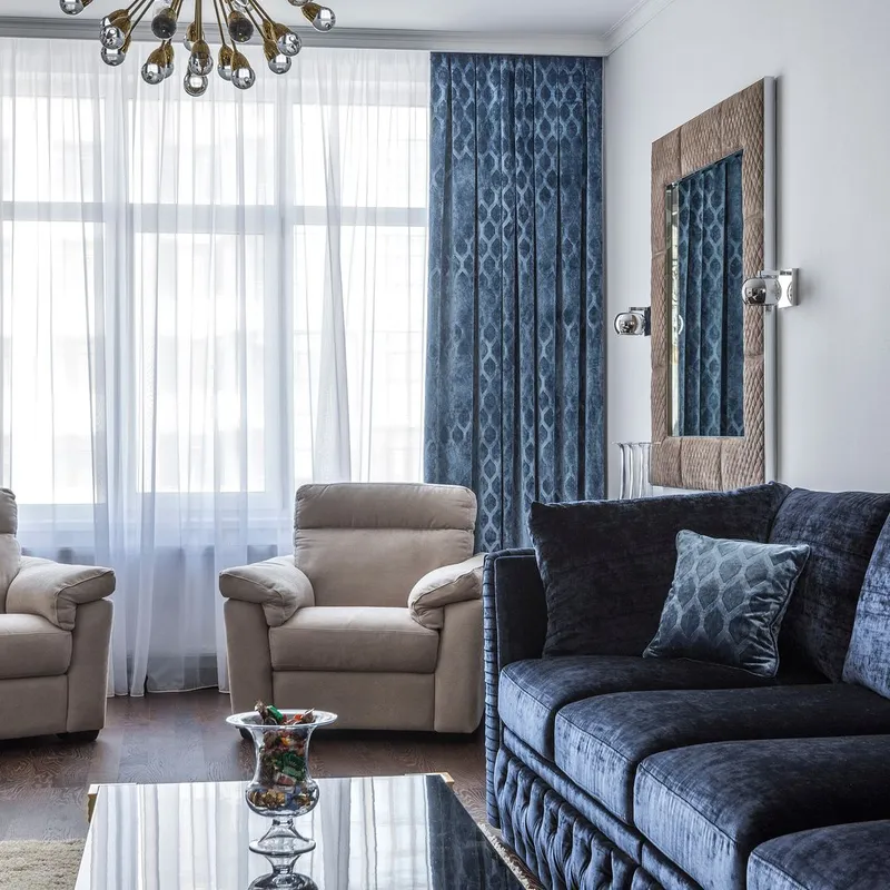 A furnished living room with a navy velvet sofa, two armchairs and a soft rug underfoot